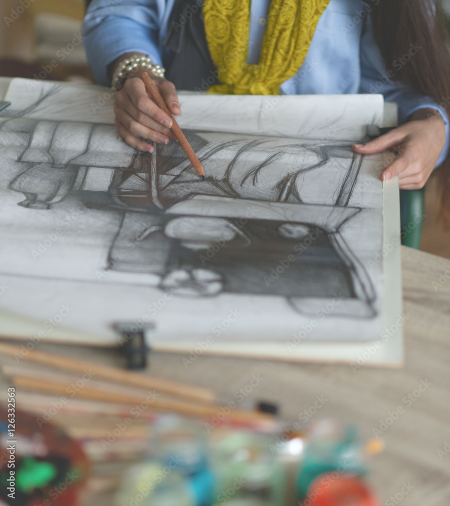 Fototapeta premium Young woman drawing a picture. Selective focus and small depth of field.