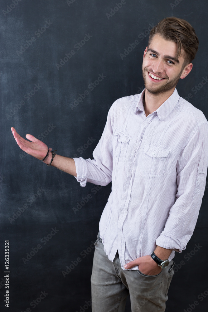 Portrait of young happy smiling teacher man standing near chalkb