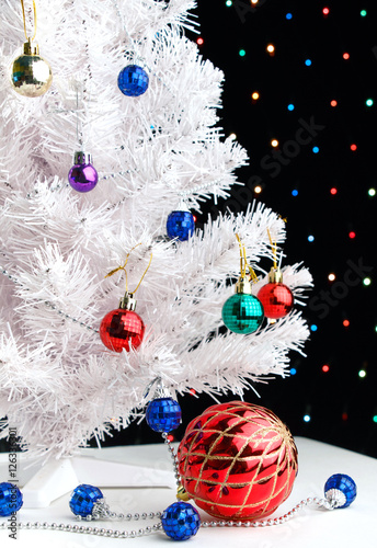 Red xmas ball near by decorated white fir-tree