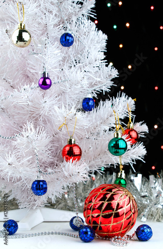 Red xmas ball near by decorated white fir-tree