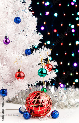 Red xmas ball near by decorated white fir-tree