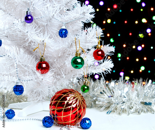 Red xmas ball near by decorated white fir-tree