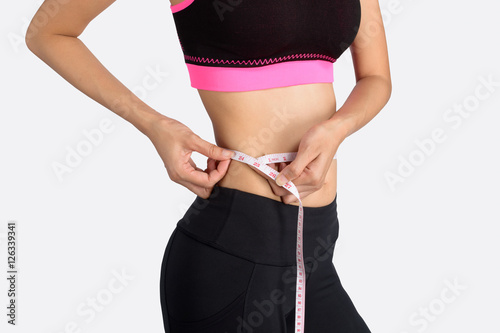 Young beautiful woman measuring her waist.