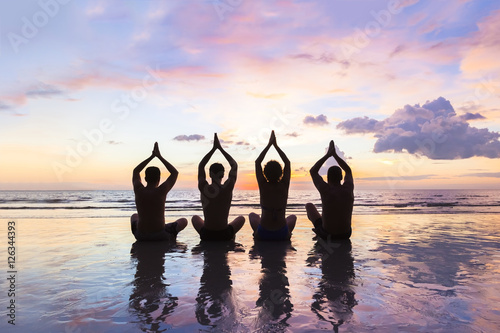 Group of people practicing meditation and yoga  beach  sunset  harmony