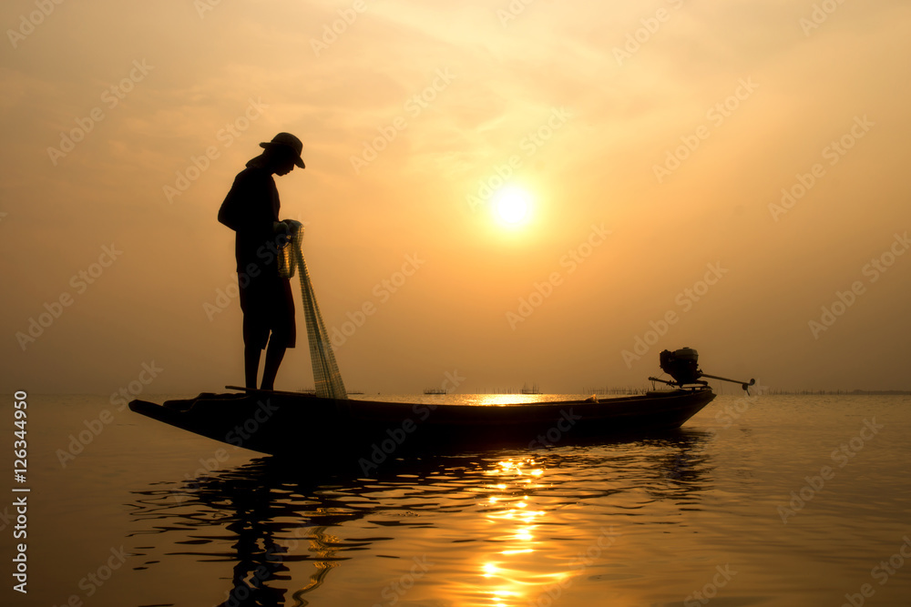 Silhouettes fisherman throwing fishing nets during sunset.