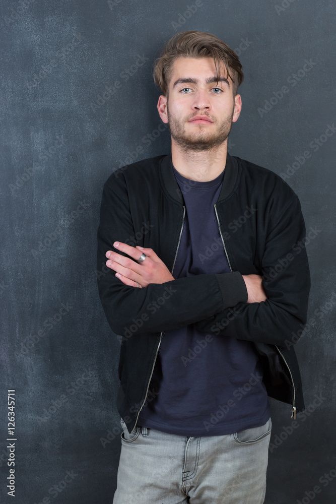 Happy young man standing with arms crossed over blackboard backg Happy young man standing with arms crossed over blackboard backg