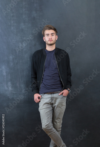 Trendy relaxed young man with a modern haircut standing against