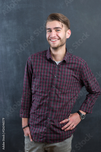 sexy fashion man or student dressed casual smiling against chalk