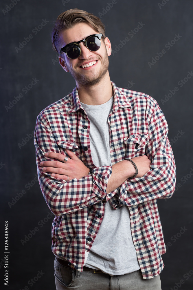 Trendy relaxed young man with a modern haircut standing against Trendy relaxed young man with a modern haircut standing against