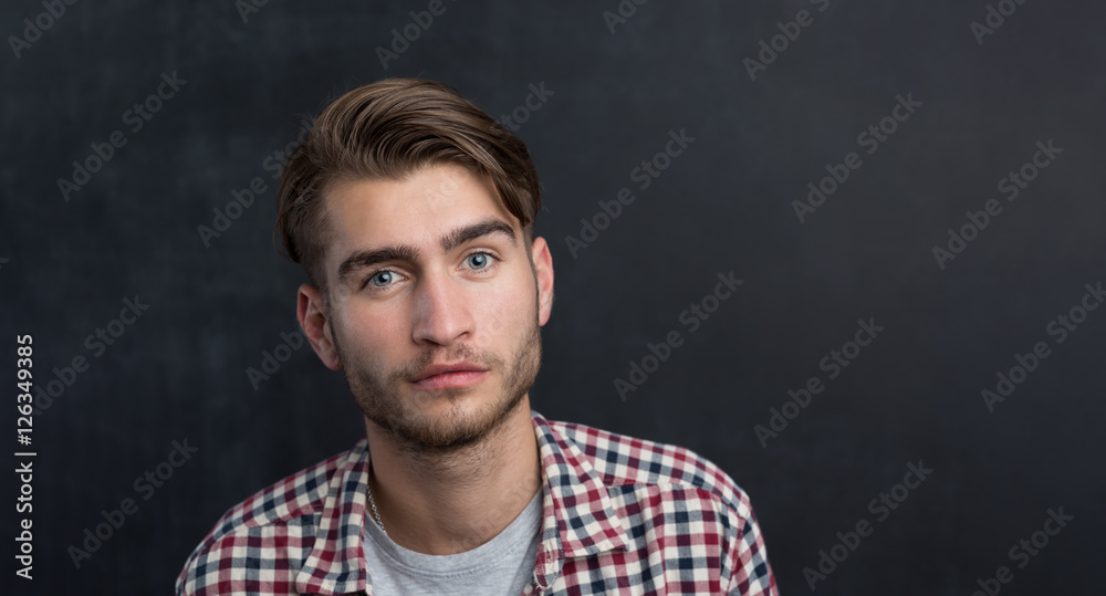 Obraz premium Handsome young student in shirt standing against blackboard