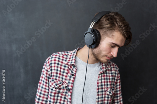 Portrait of confident young DJ with stylish haircut and headphon photo