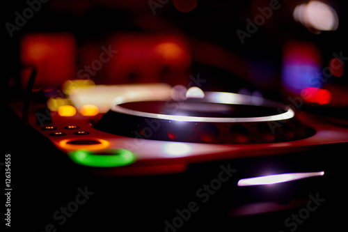 Night Club DJ playing mixing music on turntable at party
