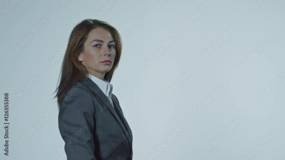 Lockdown of young businesswoman walking against grey background and throwing heaps of dollar bills to camera Lockdown of young businesswoman walking against grey background and throwing heaps of dollar bills to camera