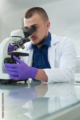 Young scientist investigating microbiological substance in micro