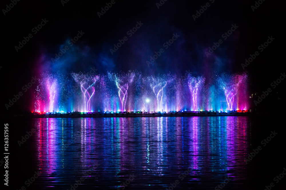 Beautiful fountain dancing show with reflection on water at night.