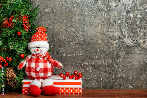 Christmas, snowman sitting on the shelf on gray background. Place for text.