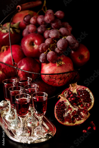 Still life on a dark background. Wine (liquor) glasses, fruits a