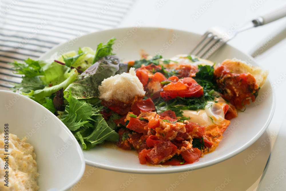 Omelette with tomatoes and greens on a white plate Omelette with tomatoes and greens on a white plate