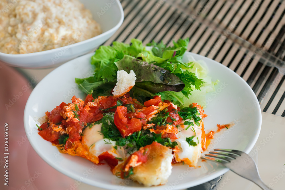 Omelette with tomatoes and greens on a white plate Omelette with tomatoes and greens on a white plate