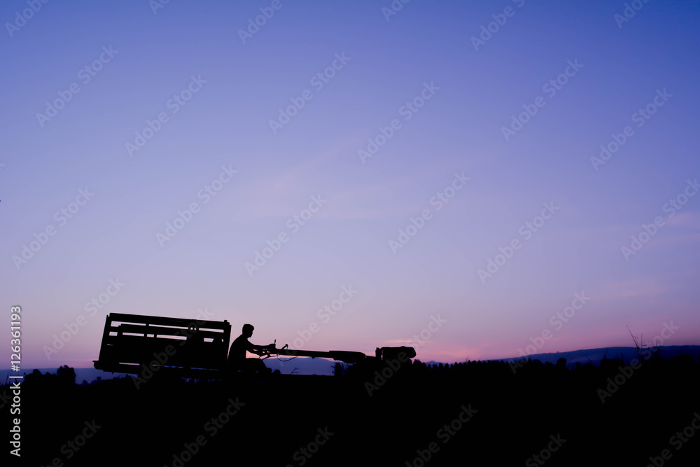 Silhouette of farmer driving tractor on field in harvest season,Happy farmer at sky sunrise in the morning