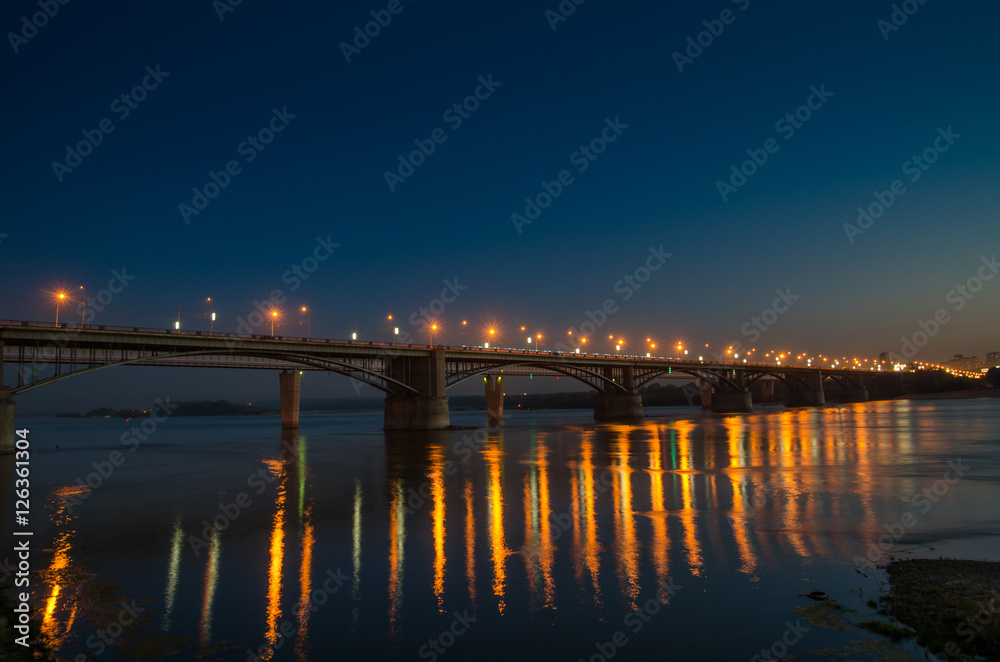 Bridge with bright lights across the river at night and reflecti