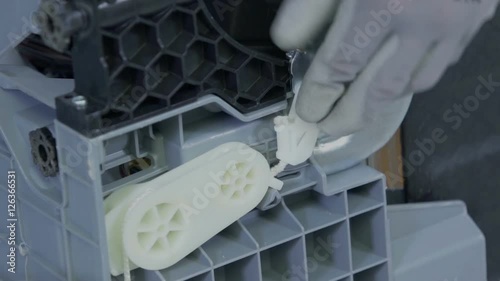 A man is opening a small white lid and he is uding a screwdriver to repair something. He is using protective gloves. Close-up shot.
 photo