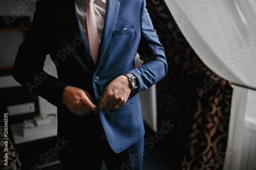 Closeup of man buttoning his jacket, business clothing concept