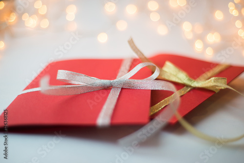 close up of two red greeting cards with ribbon bows on white background with christmas lights