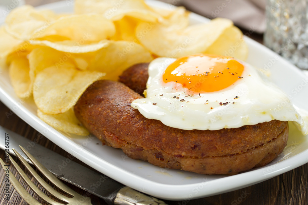 fried portuguese sausage alheira with egg and potato chips on white dish fried portuguese sausage alheira with egg and potato chips on white dish