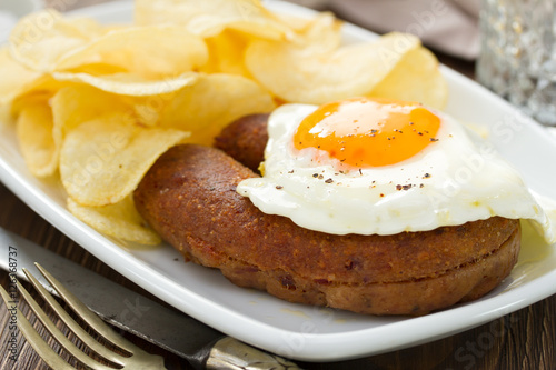 fried portuguese sausage alheira with egg and potato chips on white dish photo