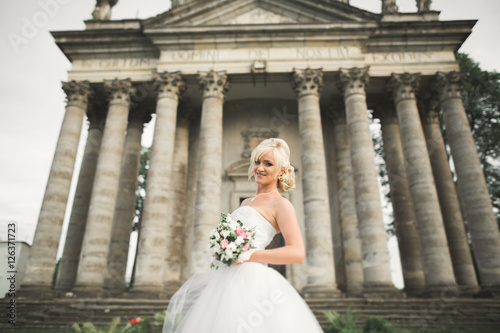 Beautiful stylish blonde bride posing near old castle