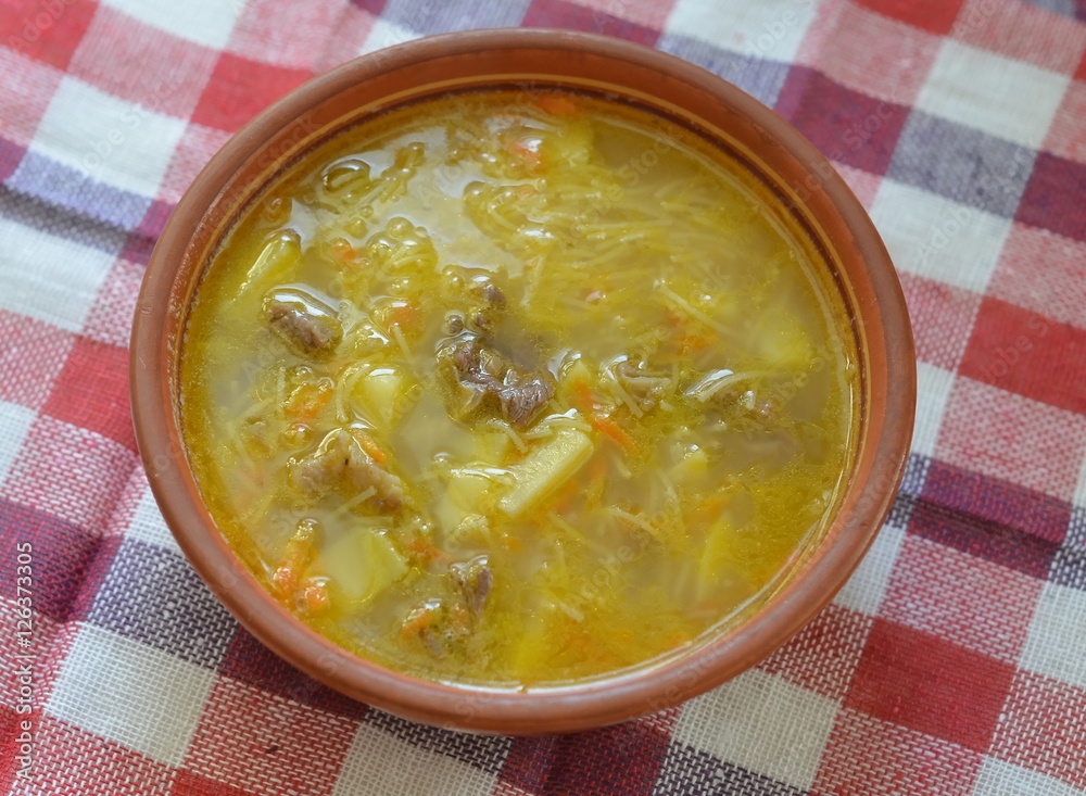 Meat soup with potatoes and noodle in an old ceramic plate Meat soup with potatoes and noodle in an old ceramic plate