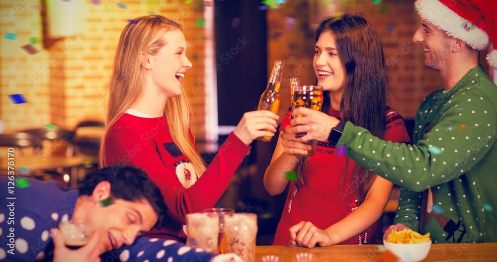 Composite image of smiling friends having drinks during christma