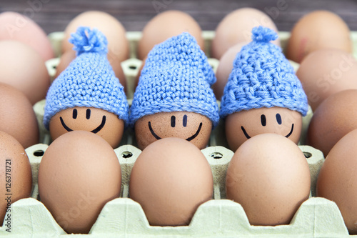 Three eggs wearing blue hats, stay together with happy faces.