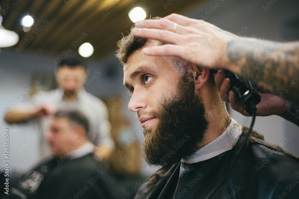 Fototapeta premium Bearded man getting his hair and beard cut at the local barber s