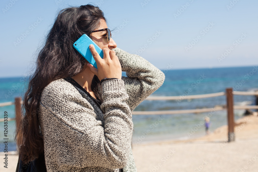 young woman talking on telephone in the beach