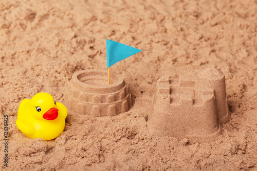 Obraz na plátně Colosseum and castle, flag, rubber duck in sand. Background.