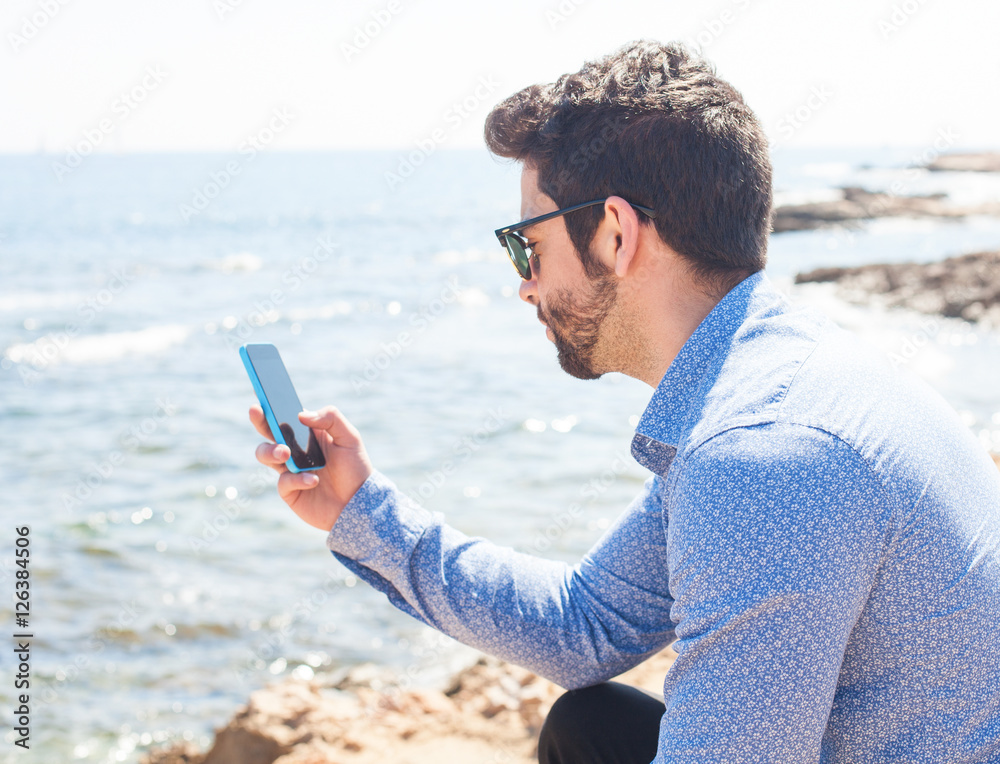 young man using his telephone in the beach
