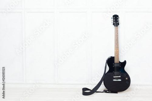 guitar propped in front of a white wall
