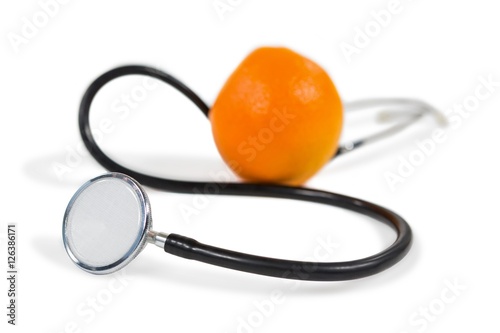 Stethoscope and orange on white background