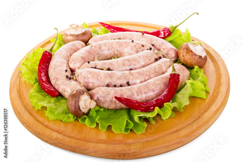 Wooden board with raw sausages, mushrooms, lettuce and pepper isolated.