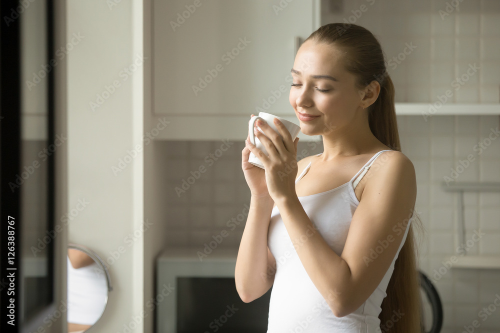 Portrait of a smiling young girl inhaling aroma of her drink, her eyes closed, lifestyle Portrait of a smiling young girl inhaling aroma of her drink, her eyes closed, lifestyle