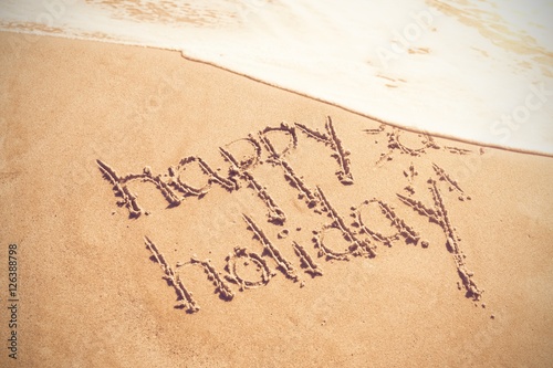 Happy holiday written text on sand