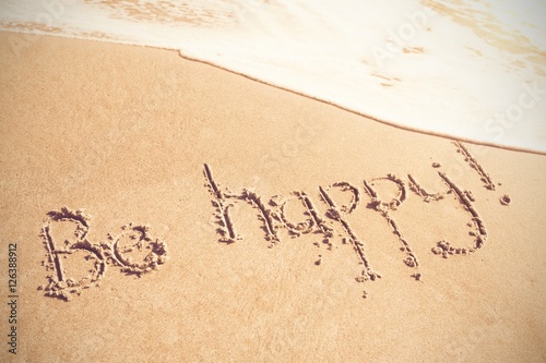 Be happy text written on sand