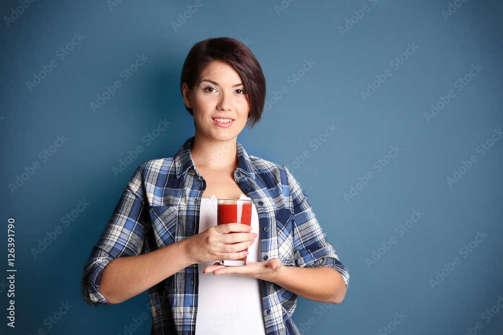 Young beautiful woman with glass of tomato juice, on grey background Young beautiful woman with glass of tomato juice, on grey background