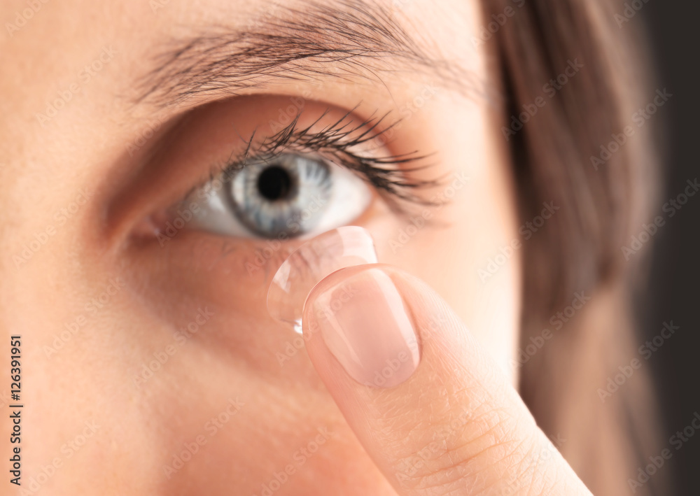 Obraz premium Close up view of young woman putting contact lens in her eye