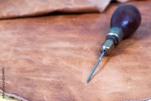 Leather craft tools on a wooden background. Leather craftmans work desk . Piece of hide and working handmade tools on a work table photo