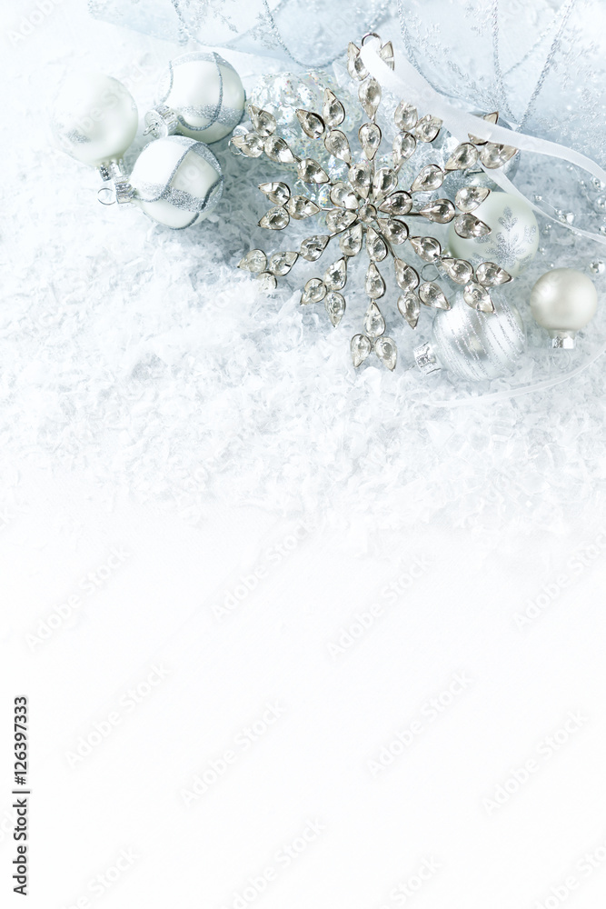 White and silver christmas decorations on a white surface with snow
White and silver christmas decorations on a white surface with snow