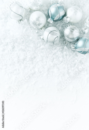 White, silver and blue christmas balls on a white surface with snow