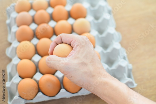 Hand holding egg with de-focus of eggs in paper tray, out of focus selected